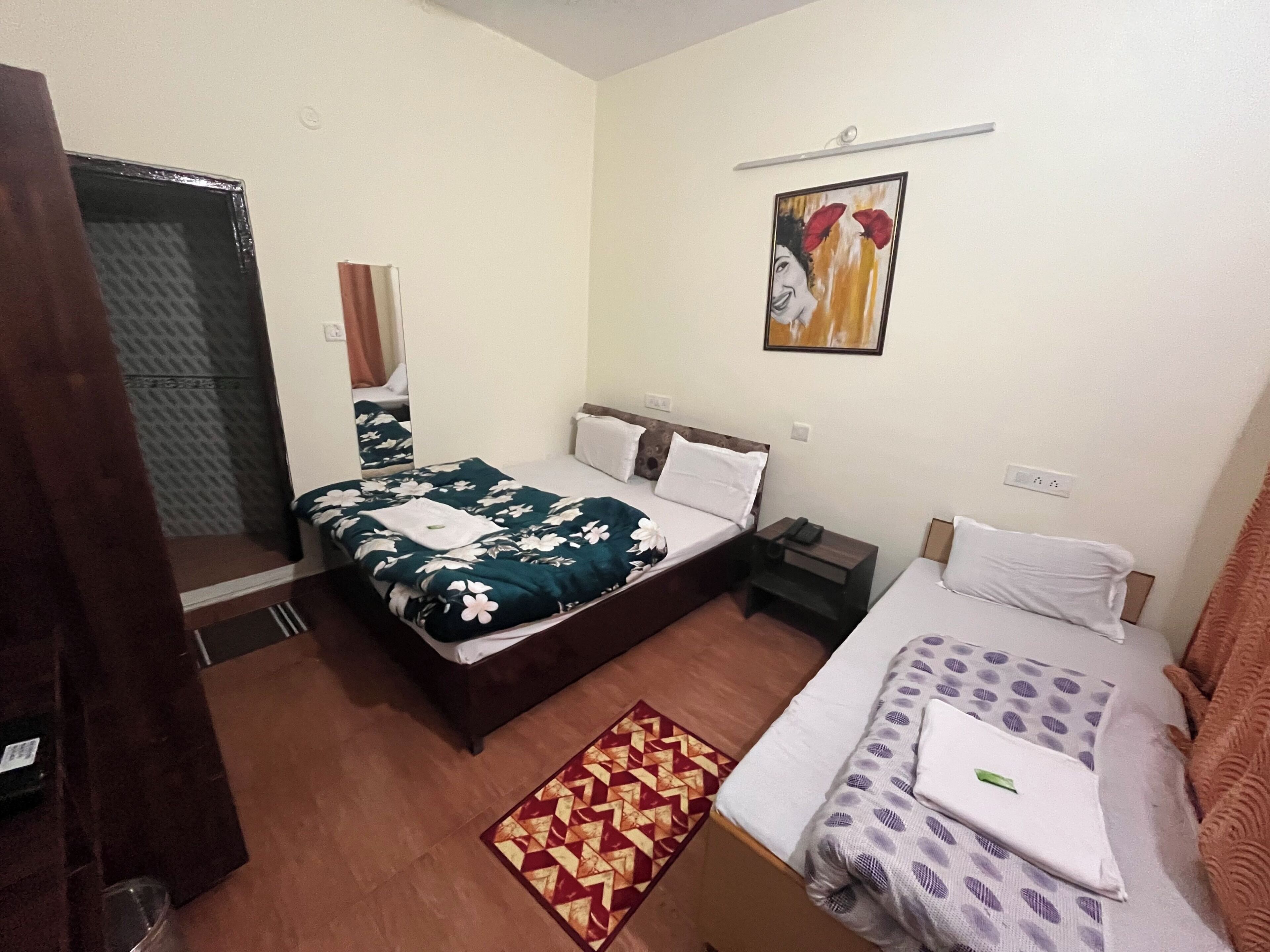 A hotel room with two beds, a painting on the wall, and a patterned rug.