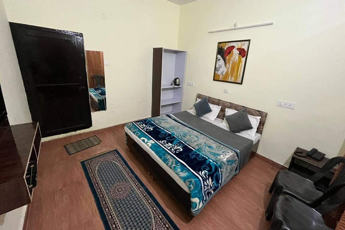 Un dormitorio con una cama, un armario, una estantería, un cuadro y una silla.