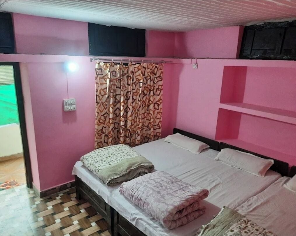 A bedroom with a bed, a patterned curtain, and a pink wall.