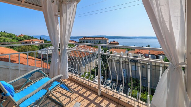 Ein Balkon mit Blick auf das Meer, einen Pool und Gebäude im Hintergrund.
