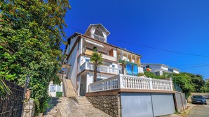 Ein mehrgeschossiges Gebäude mit Balkonen, einer Steintreppe und einer Garage.