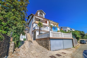 Ein mehrgeschossiges Gebäude mit Balkonen, einer Steintreppe und einer Garage.