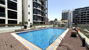 Piscina rectangular con una escalera de metal a un lado, rodeada por una cubierta de madera.
