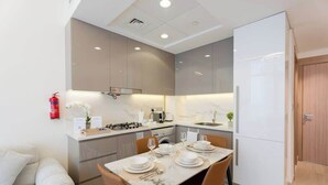 Una cocina moderna con una mesa de comedor para cuatro personas, horno empotrado y refrigerador.