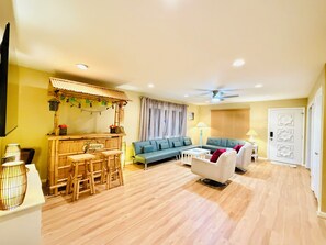 Ein Wohnzimmer mit Sofa, Esstisch und Barbereich mit einem 'WELCOME'-Schild.