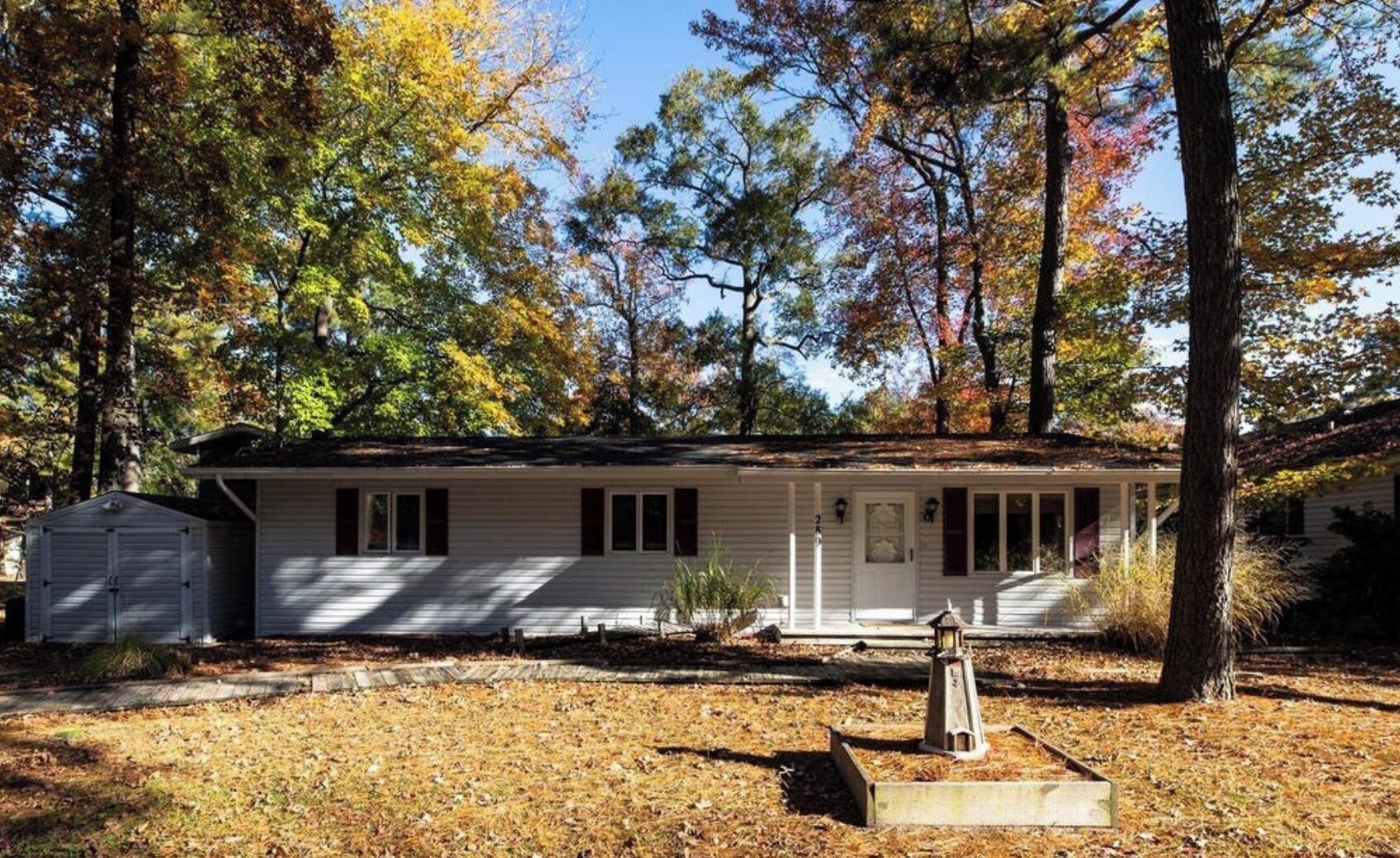 A single-story house with a front porch, a garage, and a small shed.