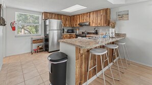 Una cucina moderna con mobili in legno, un frigorifero in acciaio inossidabile, un forno a microonde e un piano di lavoro in granito.