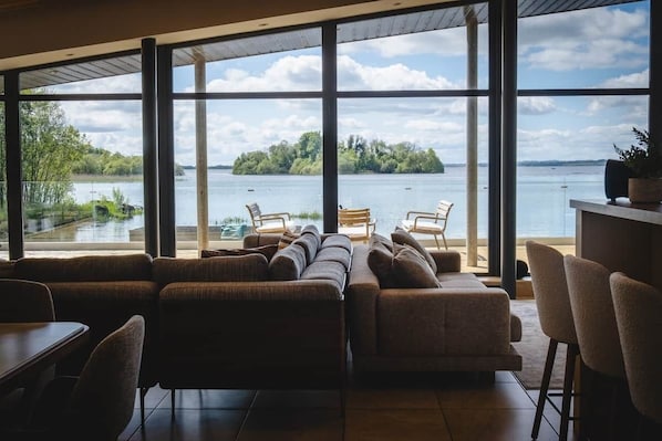 A modern interior with large windows, a sofa set, and a dining area.