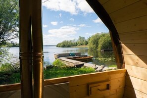 Una baita in legno con vista su un lago tranquillo, un pontile e vegetazione.