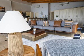 A living room with a sofa, a coffee table, a lamp, and a view of the kitchen.