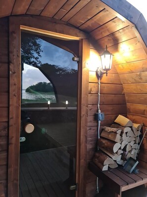 Una baita di legno con una porta in vetro, un lanternino e una pila di legna da ardere.