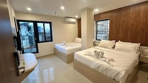 Habitación de hotel con dos camas, un lavamanos y una ventana con vistas a una zona industrial.