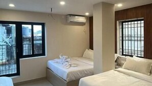 Una habitación de hotel moderna con dos camas, un escritorio y un ventanal grande.