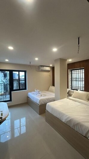 Una habitación de hotel moderna con dos camas, un escritorio y un ventanal grande.