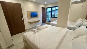 Una habitación de hotel con una cama grande, un televisor montado en la pared, una ventana con vistas y una puerta.