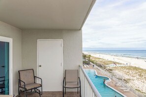 Ein Balkon mit zwei Stühlen, einem Pool und Blick auf den Strand.