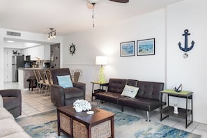 Ein Wohnzimmer mit einer Couch, Sesseln, einem Couchtisch und einem Essbereich mit Stühlen und einem Tisch.