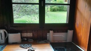 Una cocina compacta con lavadora, horno, cocina y ventana con vistas a zonas verdes.