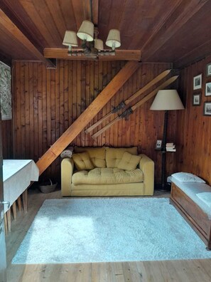 A wooden interior with a sofa, a lamp, and a ceiling fan.
