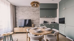 A modern kitchen with a dining area, a television, and a large window with curtains. - Musa Nowoczesne wn Trze w Sercu Miasta Nowy Port (gmina Parzęczew)