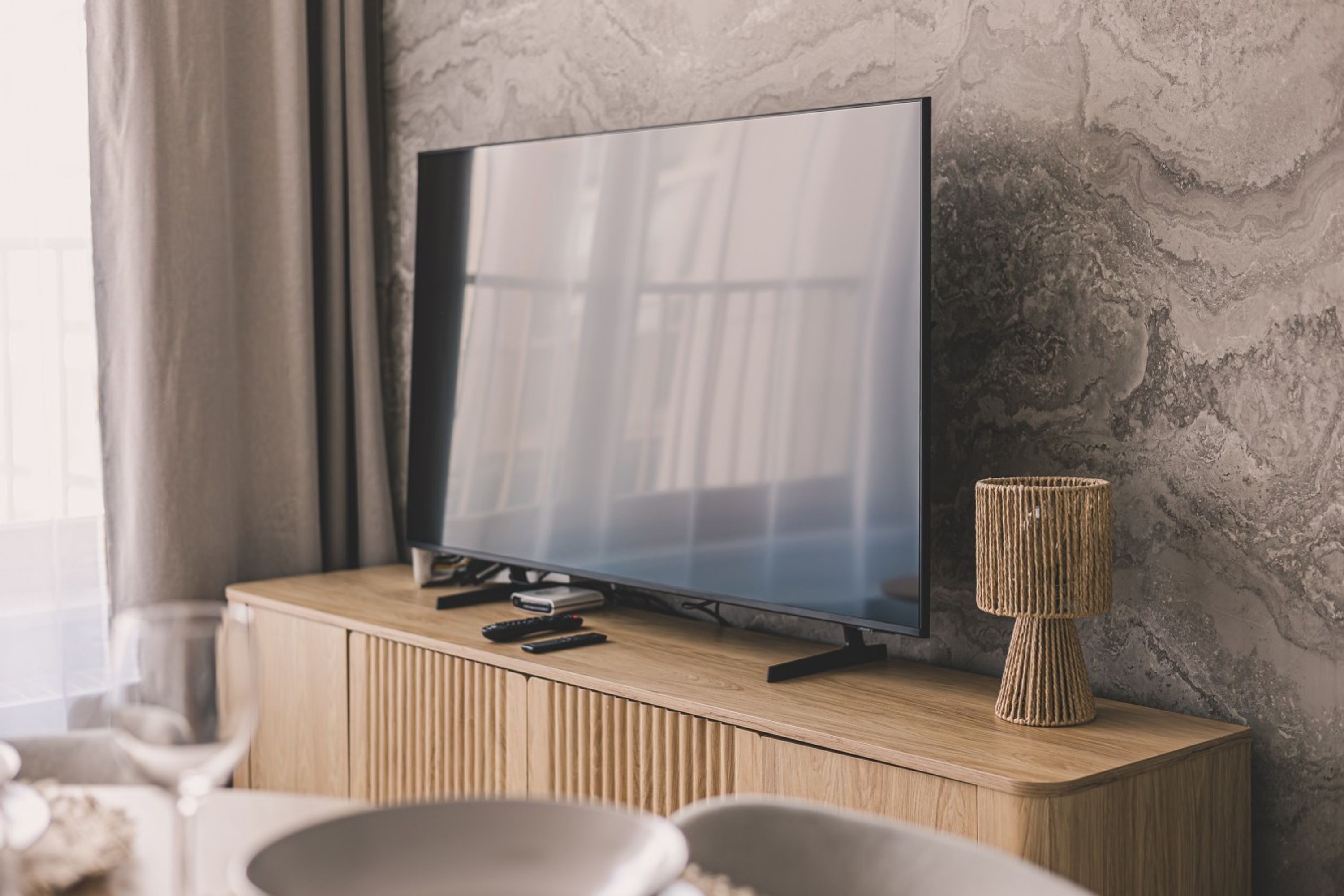 Un televisor sobre un mueble de madera con una pared texturizada al fondo.