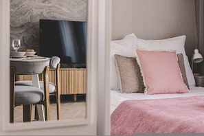 Et hotelværelse med en seng, en stol, et bord og et fjernsyn.