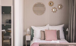A neatly arranged bedroom with a bed, bedside tables, and a nightstand.