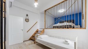 A room with a bed, a wooden staircase, a white door, and a clock on the wall. - Ocean Horizon Apartment Sea View Parking (Vlorë)
