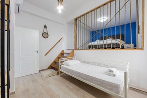 Ein Zimmer mit einem Bett, einer Holztreppe, einer weißen Tür und einer Uhr an der Wand.