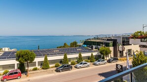 A modern building with solar panels, parked cars, and a view of the sea. - Ocean Horizon Apartment Sea View Parking (Vlorë)