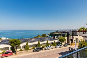 Ein modernes Gebäude mit Solaranlagen, parkenden Autos und Blick auf das Meer.