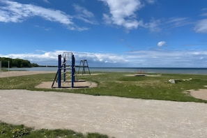 Ein Spielplatz mit Schaukeln und einer Kletterkonstruktion in der Nähe von Wasser.