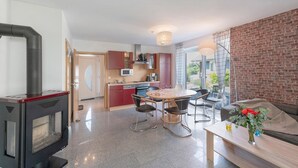 Una cucina moderna con piano cottura integrato, una zona pranzo con tavolo e sedie, e un soggiorno con divano e tavolino.