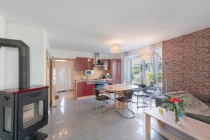 A modern kitchen with a built-in stove, a dining area with a table and chairs, and a living area with a sofa and a coffee table.