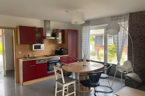 Une cuisine moderne avec des meubles de rangement rouges, une table à manger et des chaises.