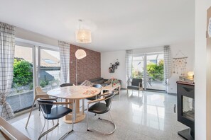 Eine moderne Küche mit Essbereich, großen Fenstern und einem Kamin.