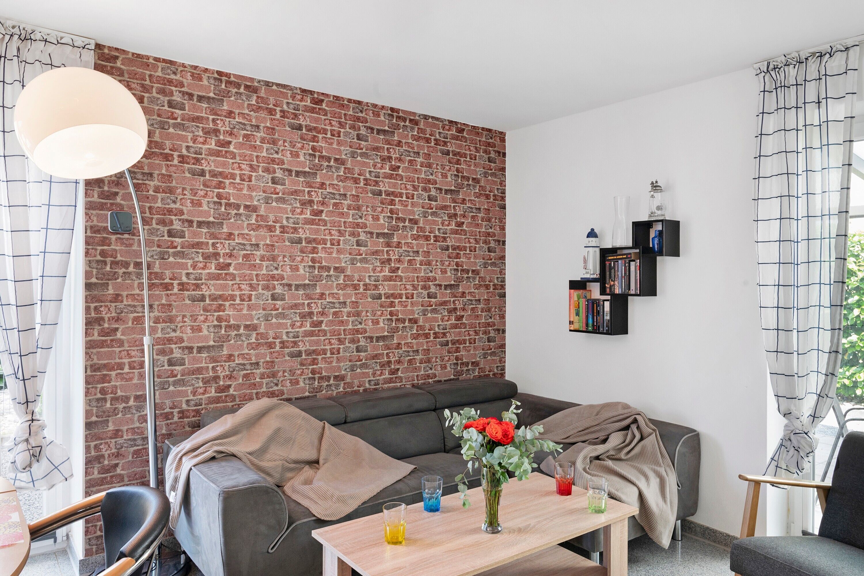 Ein modernes Wohnzimmer mit Backsteinwand, einer Couch, einem Couchtisch und einem Bücherregal.