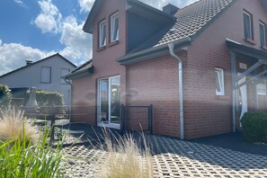 Een tweelaags bakstenen huis met een duidelijke voordeur, een klein portiek en een heldere lucht.