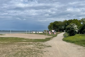 Un sendero arenoso que lleva a una playa con un parque infantil y árboles.