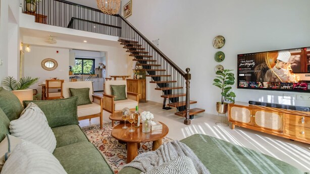 A spacious living room with a staircase, a dining area, and a TV mounted on the wall. - Casa Calma Scenic 3BR Duplex With Jacuzzi (Oxel)