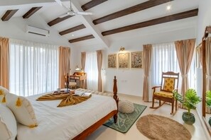A bedroom with a bed, a chair, a desk, and a potted plant. - Casa Calma Scenic 3BR Duplex With Jacuzzi (Oxel)