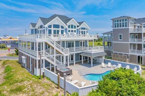 A multi-story residential building with a pool, outdoor seating, and a staircase leading to the upper levels.