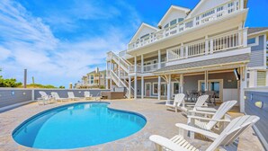 A pool area with lounge chairs and a two-story building with balconies.