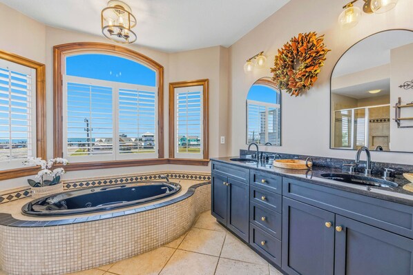 Une salle de bain avec une grande baignoire, un meuble-lavabo et un grand miroir.
