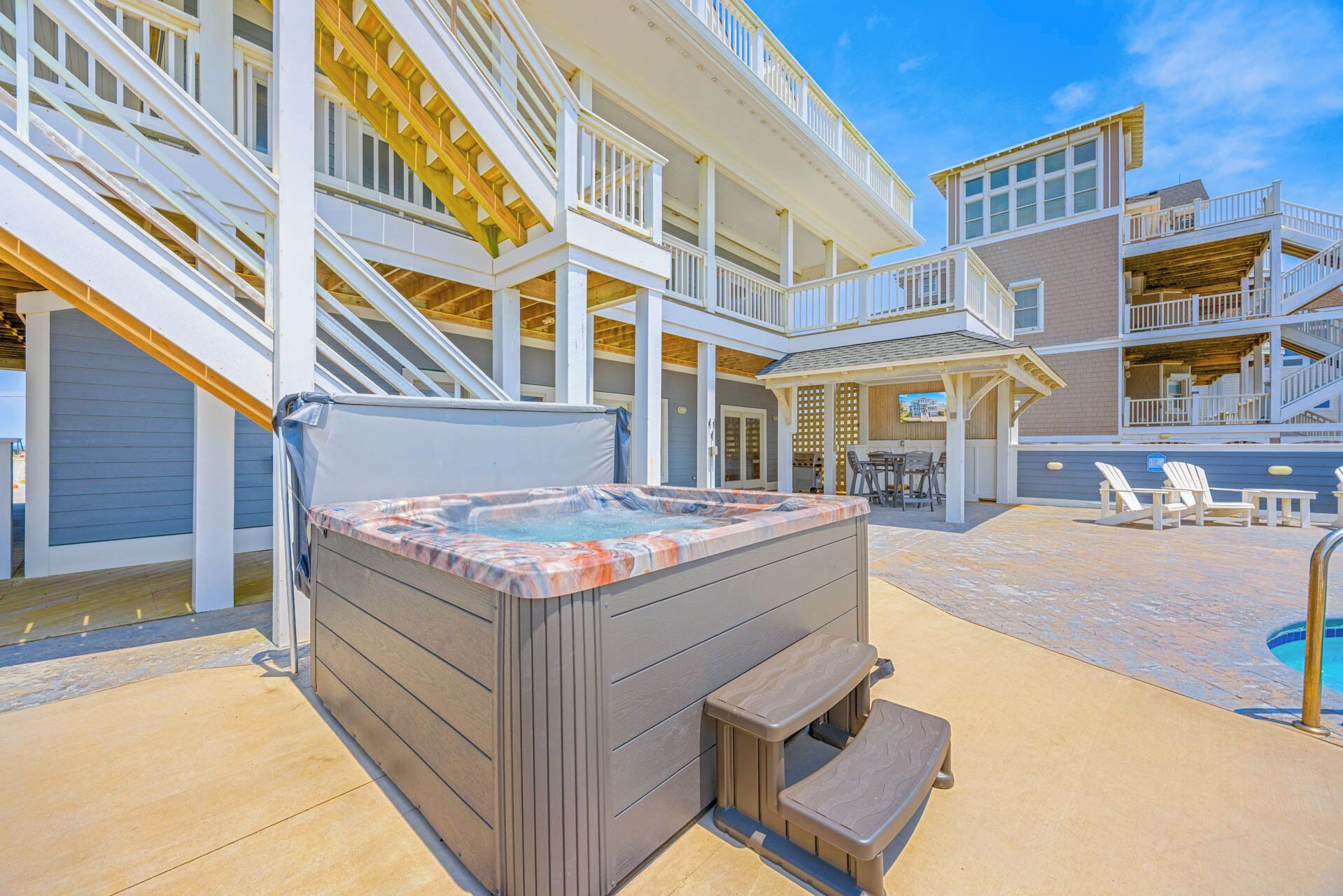 A multi-level outdoor deck with a hot tub, seating area, and pool.
