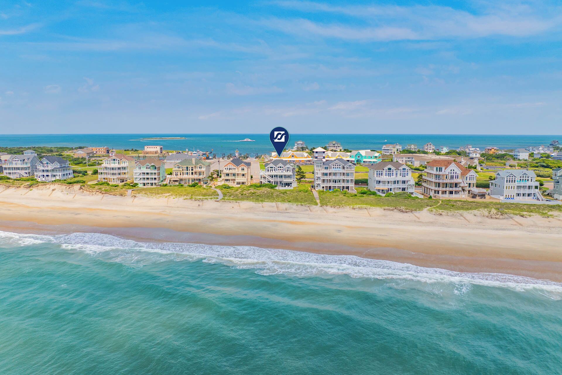 A coastal residential area with beachfront properties, a clear sky, and a calm sea.