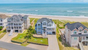 A beachfront residential area with multiple houses, a sandy beach, and the ocean in the background.