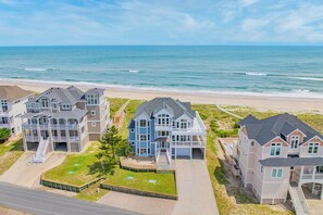 A beachfront residential area with multiple houses, a sandy beach, and the ocean in the background. - Oceanfront, Dog Friendly Home in Hatteras with Pool, Hot Tub, Game Room (Hatteras)