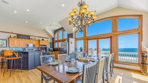 A spacious kitchen with a large island, wooden cabinetry, and a view of the ocean.
