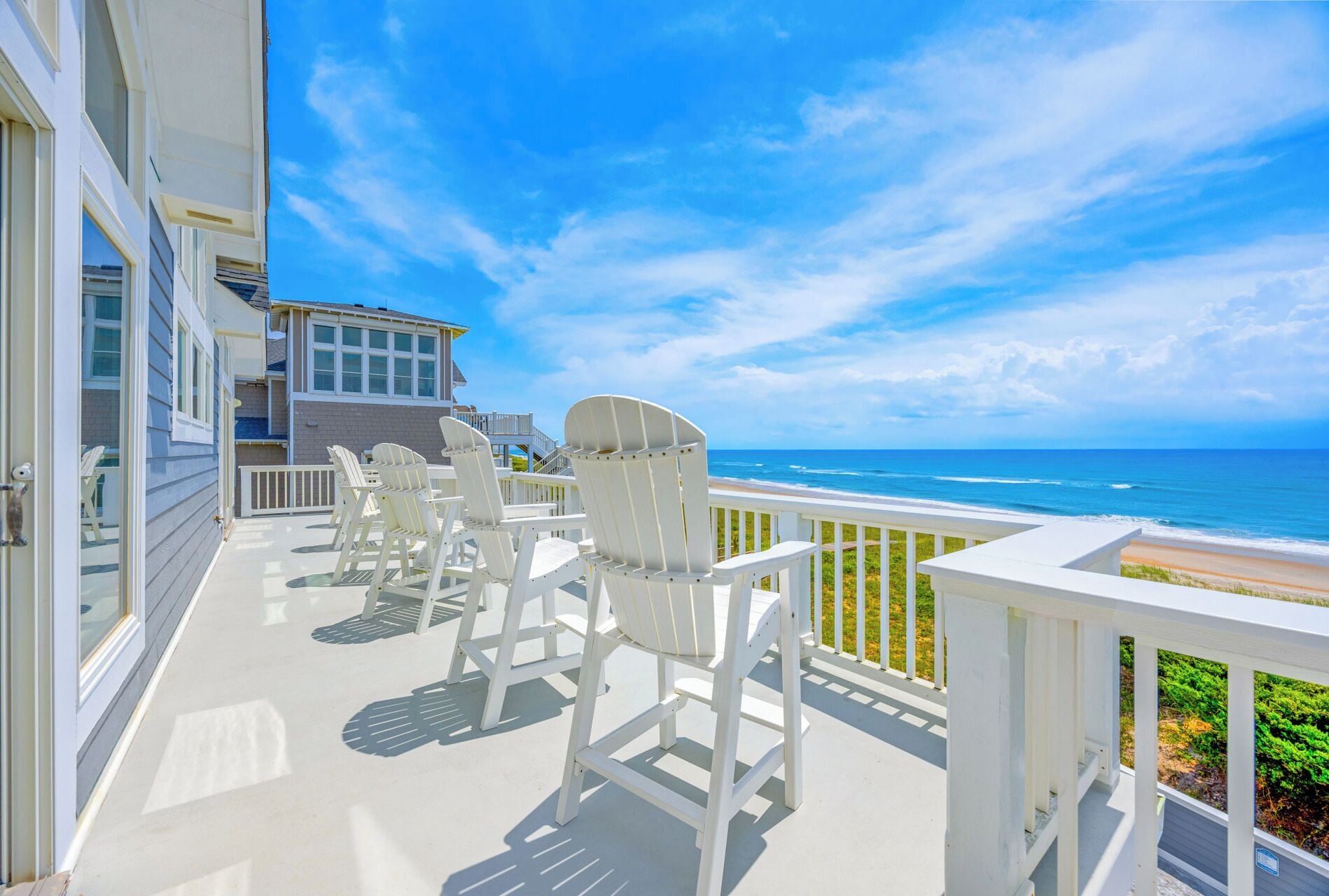 An expansive beachfront deck with coastal seating offers sweeping ocean views and direct beach access, ideal for morning coffee or sunset gatherings.